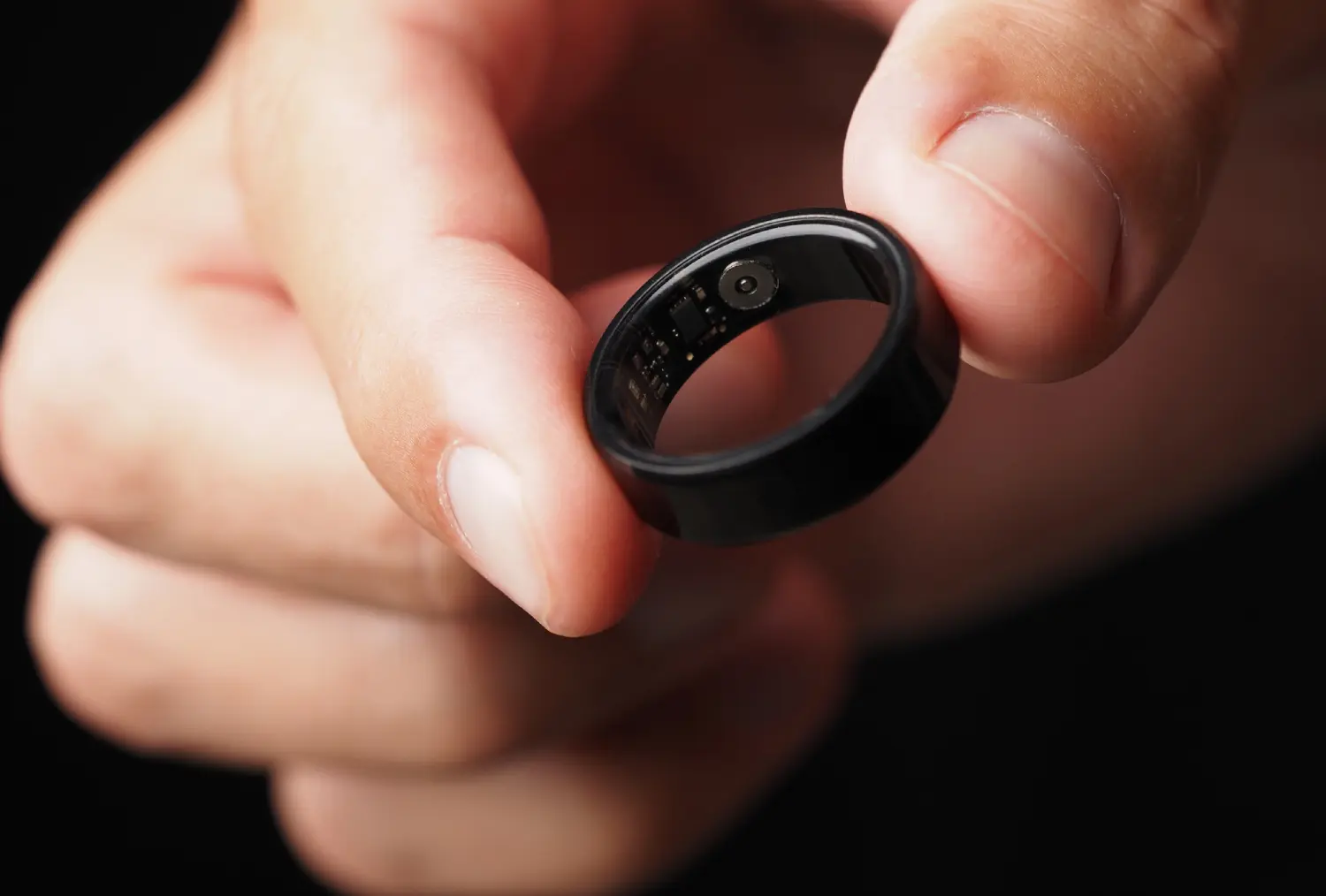 Close-up of a hand holding a black ring with engraved details.